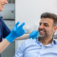 Patient smiling at dental assistant holding clear aligner