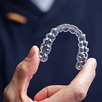 Man in blue scrubs holding Invisalign tray