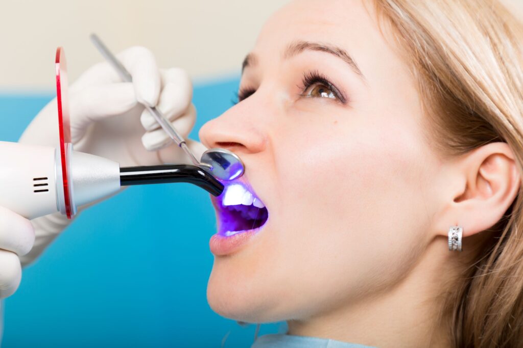 Woman with blond hair looking away from dentist while undergoing dental bonding procedure